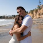 a couple hugging on the beach during their engagement session in southern california