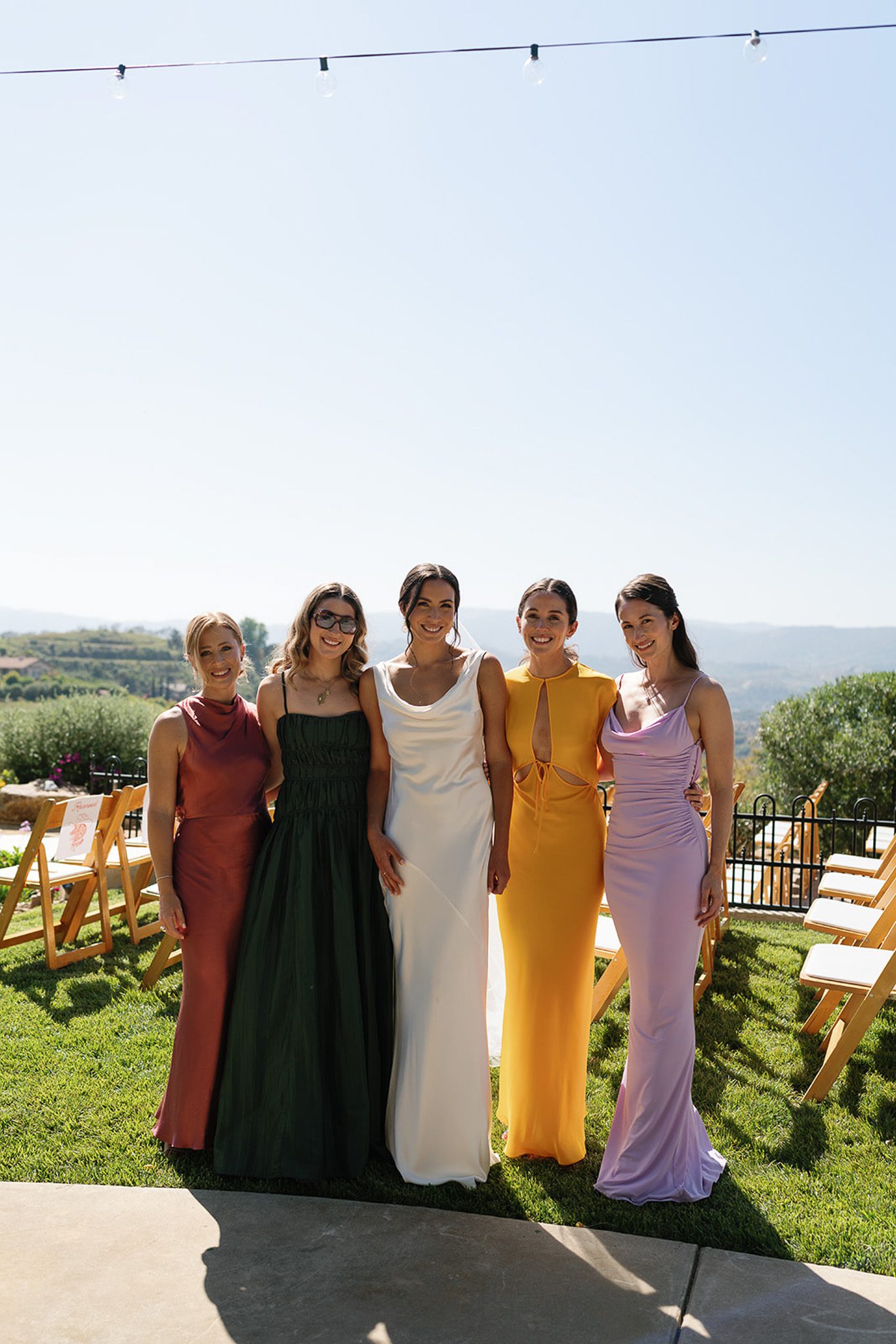 the bride and her bridesmaids smiling and wearing colorful dresses.