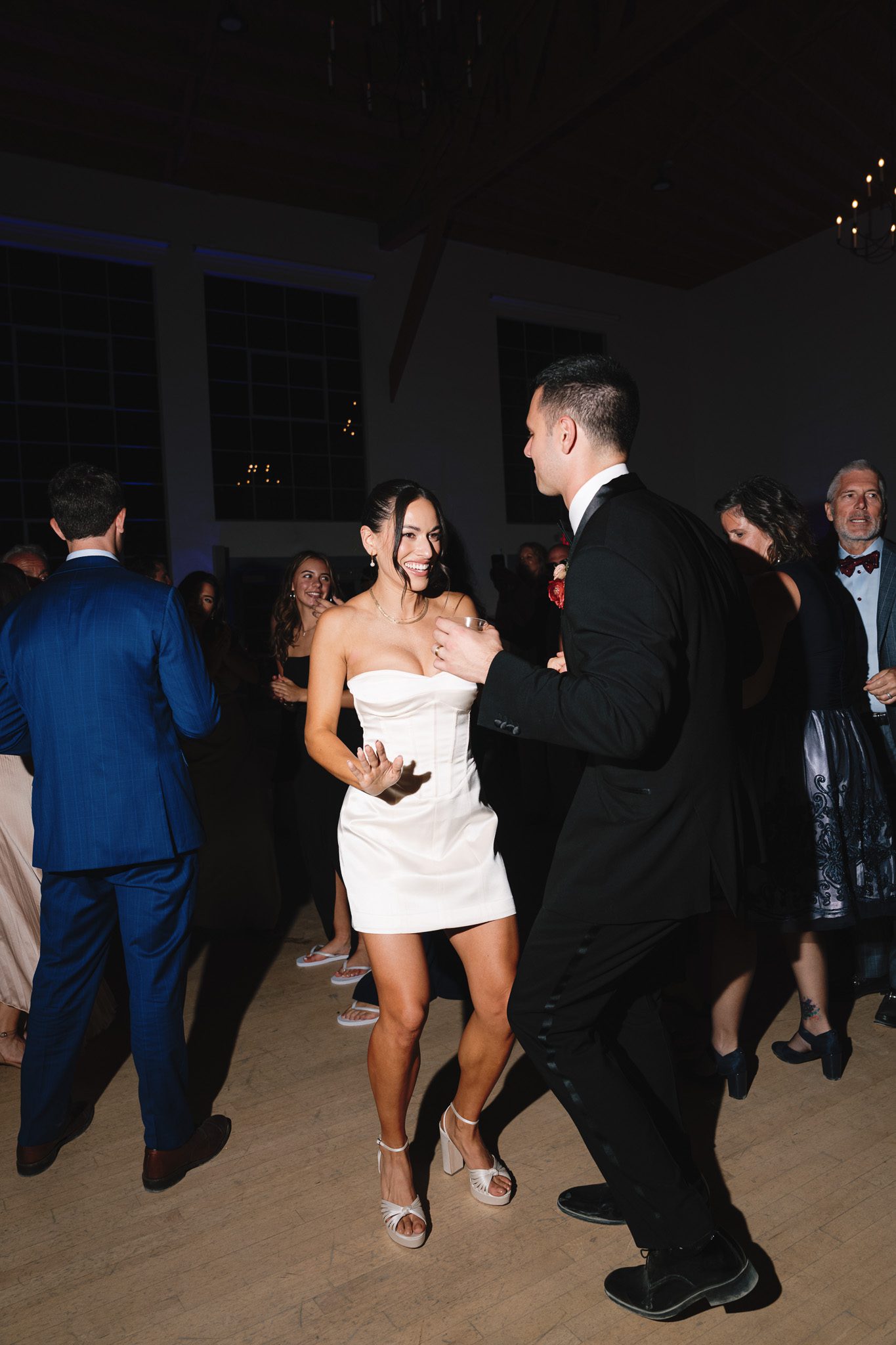 newlyweds smiling and dancing on the dance floor, posing for fun photos. 