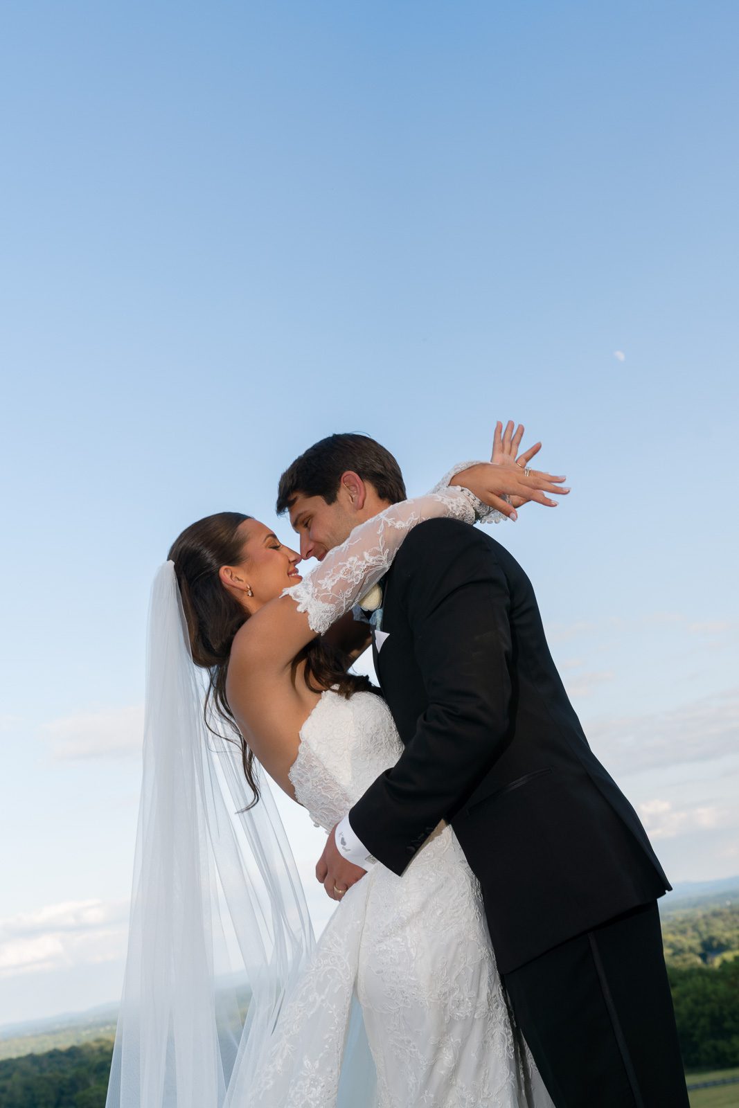 newlyweds hugging with the trees and blue sky in the background during their The View At Bluemont wedding