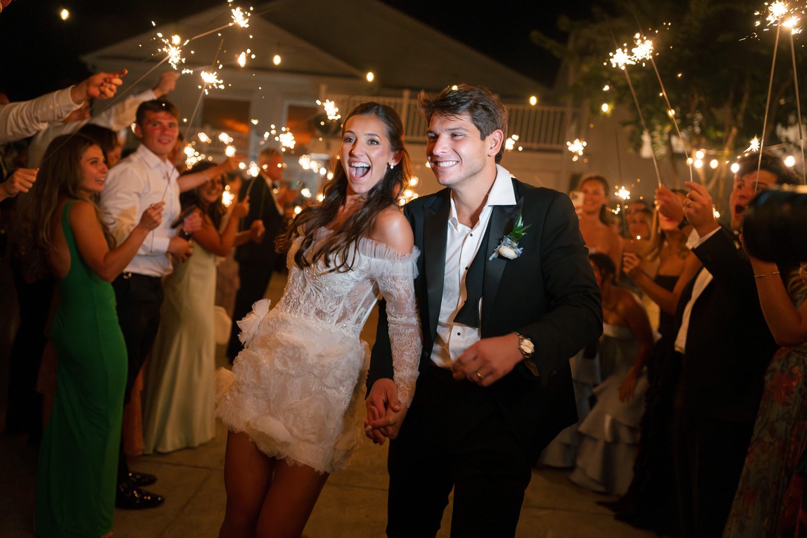 newlyweds exiting their wedding as guests raise sparklers. 