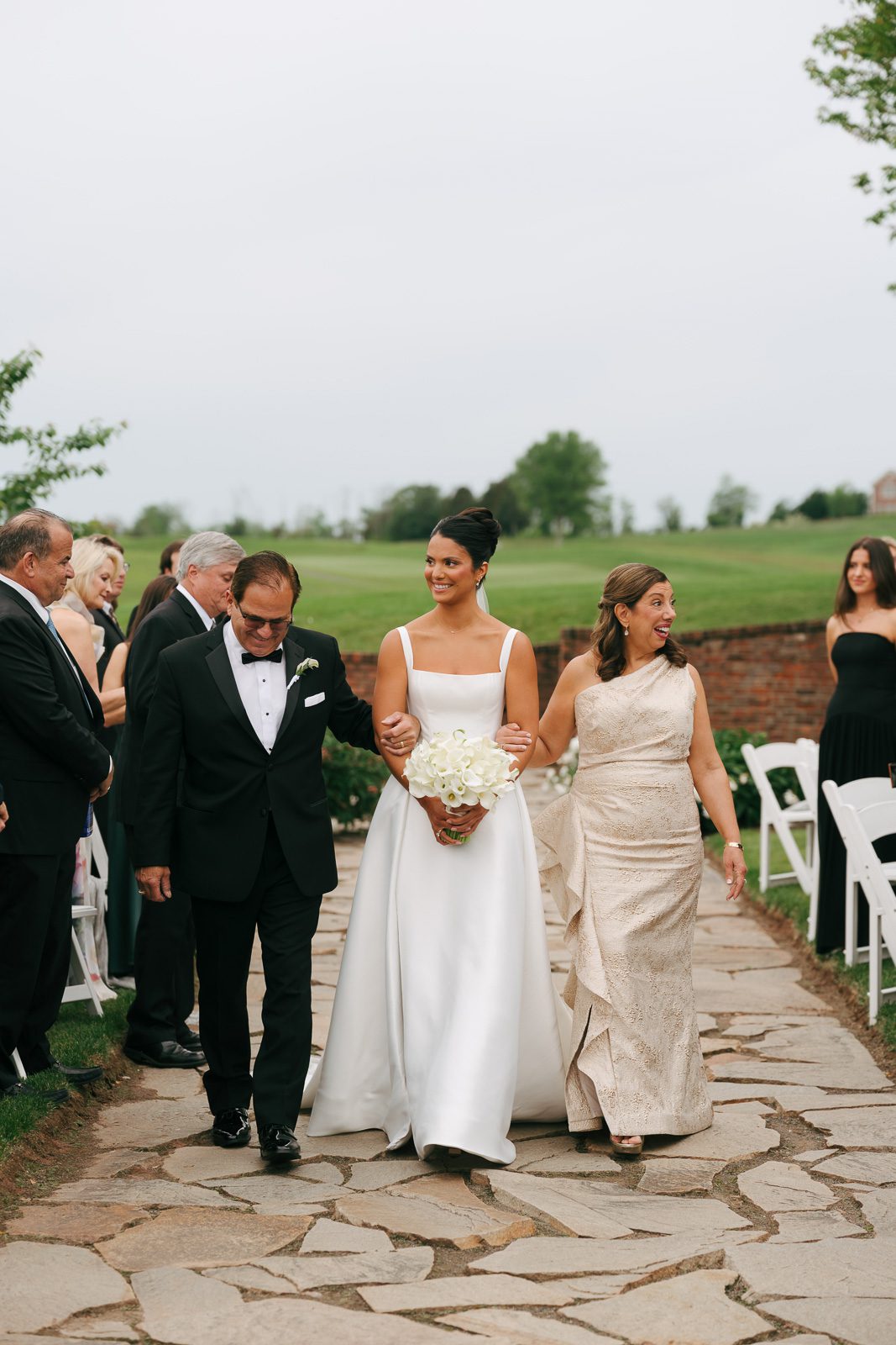 the bride walking down the aisle with her parents, a moment captured as part of her wedding day timeline. 
