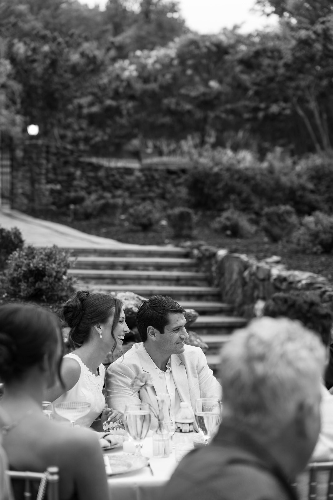 newlyweds at a dinner table smiling and laughing. 
