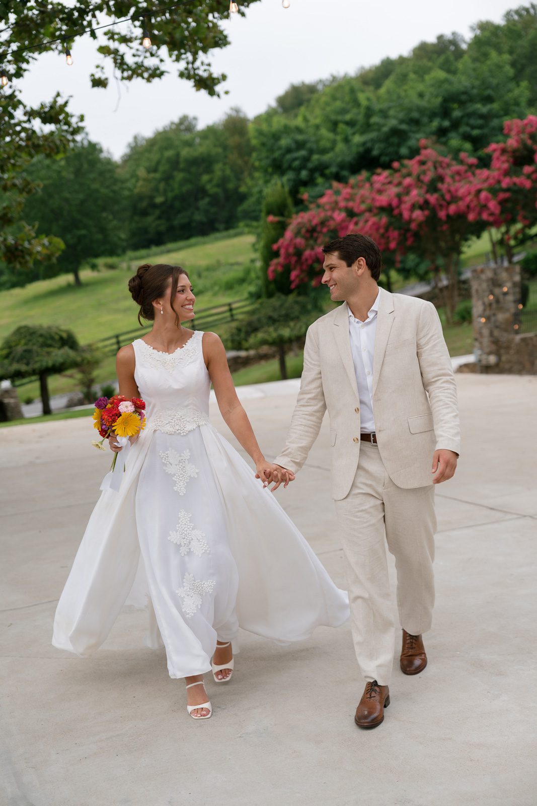newlyweds holding hands walking on a driveway during their The View At Bluemont wedding