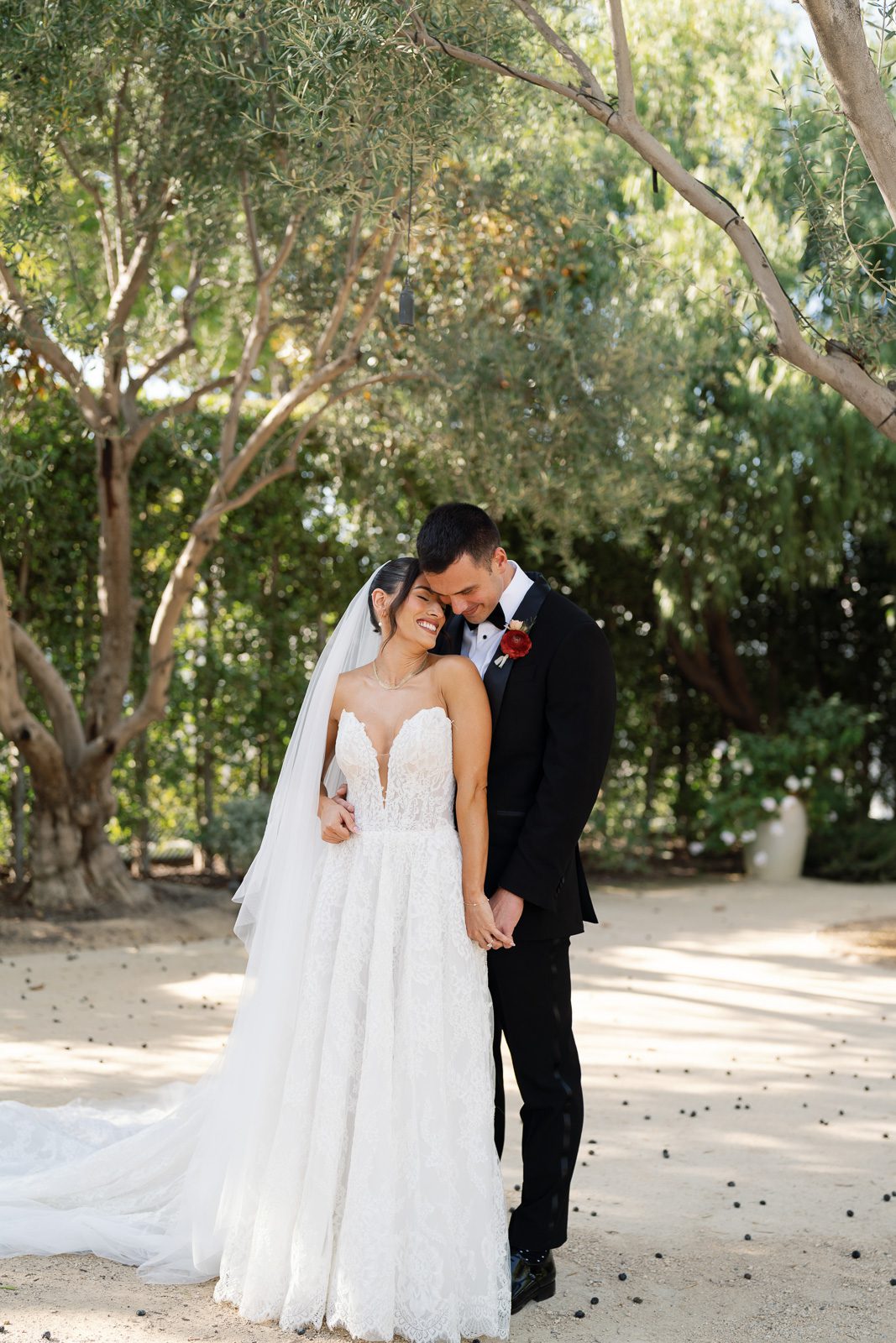 newlyweds holding hands under an olive tree during their first look, part of their wedding day timeline. 