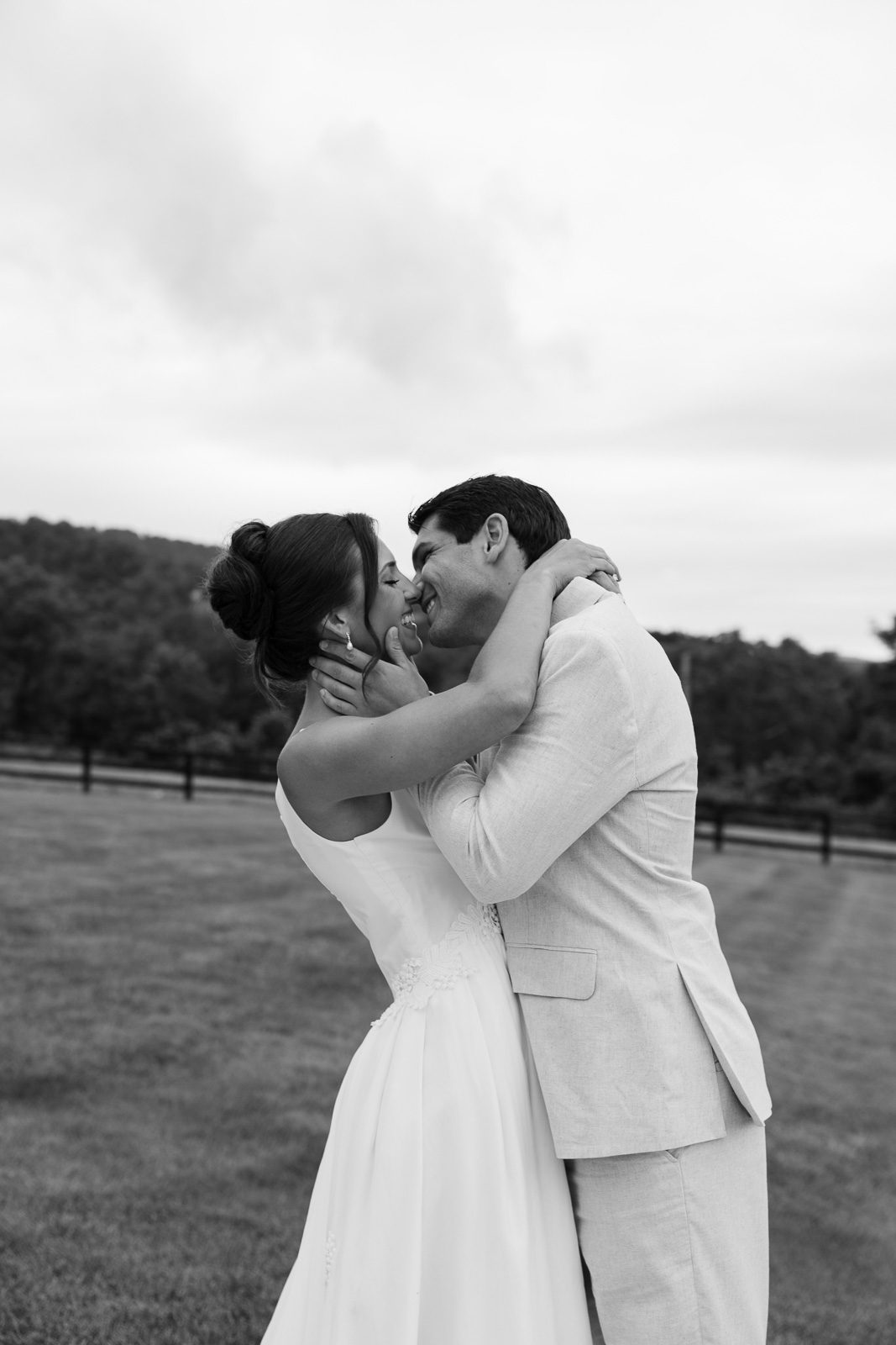 newlyweds kissing on a lawn with trees in the background during their The View At Bluemont wedding.