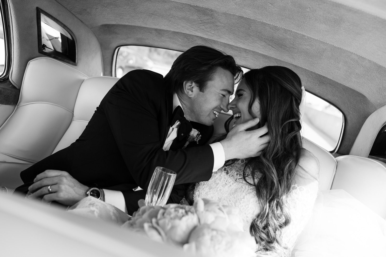 newlyweds kissing in the back of a car during their multi day wedding.