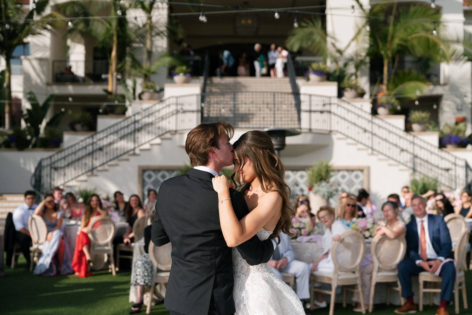the bride and groom sharing a first dance with the guests watching and smiling. 