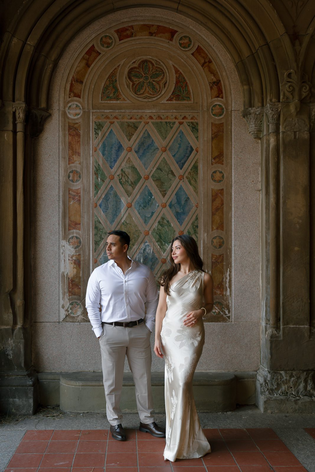 couple posing in front of tile art during their NYC engagement photos. 