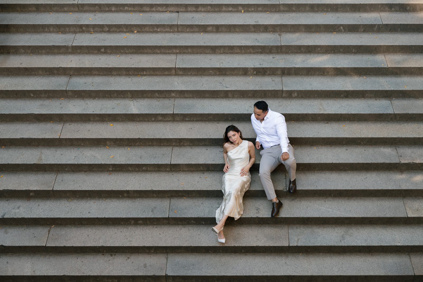 couple relaxing on a set of stairs by the bethesda terrace. 