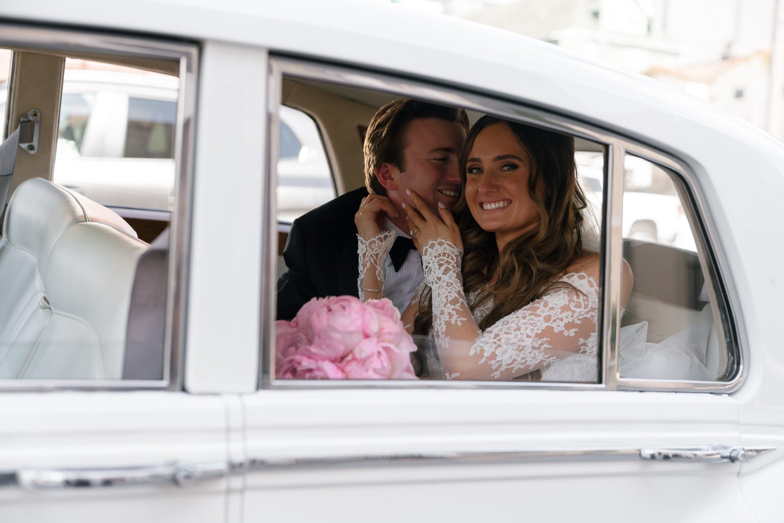 newlyweds cuddling in a Rolls Royce on their way to their wedding venue, a fun experience that makes their wedding unique. 