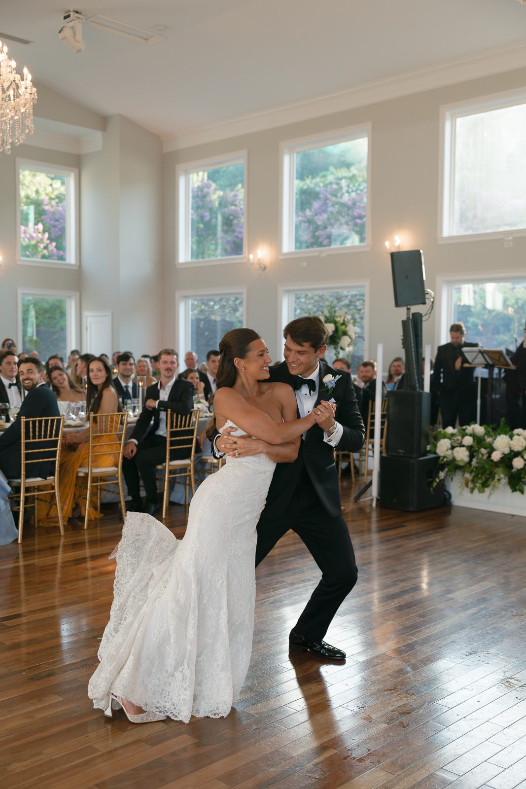newlyweds during their first dance with their friends and family looking on.