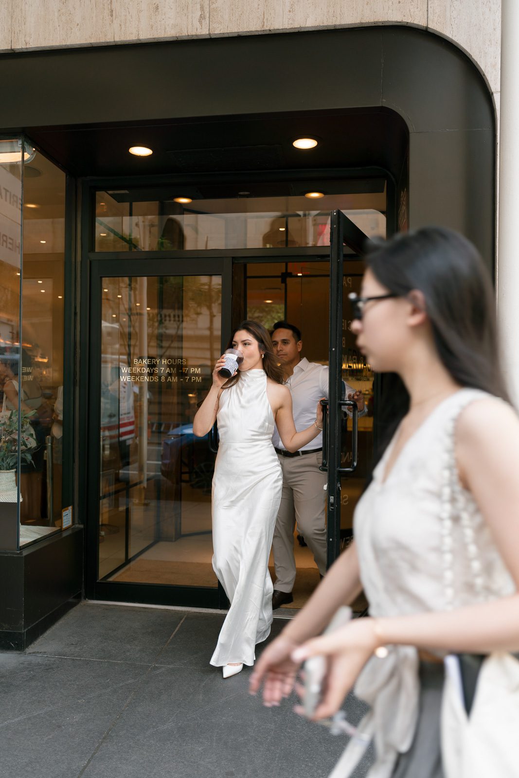 couple walking out of a bakery and coffee shop in new york while a pedestrian walks in front of them.