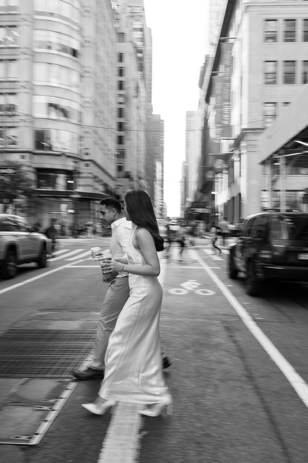 couple walking across a busy street during their NYC engagement photos. 
